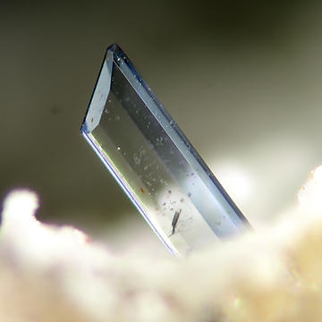 a transparent, pale blue crystal of vivianite, containing some growth defects, which appear as speckles