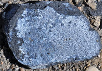pale blue weathering crust of vivianite atop a dark blue rock